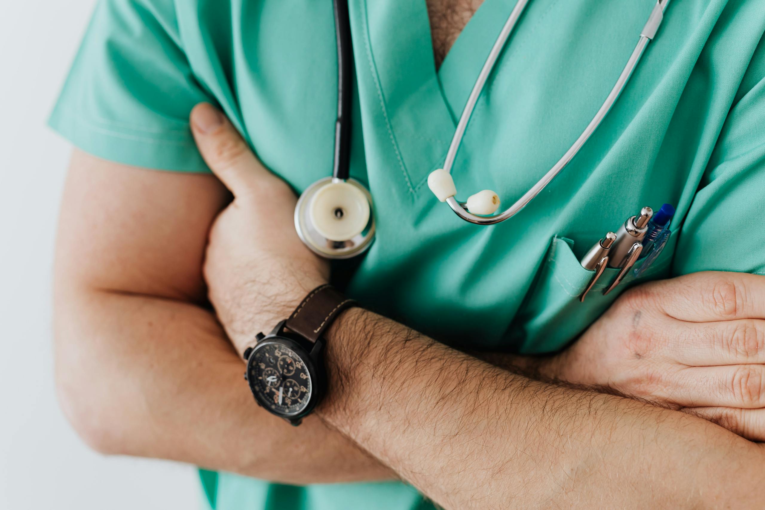 Doctor in scrubs with folded arms and stethoscope symbolizing confidence and healthcare expertise