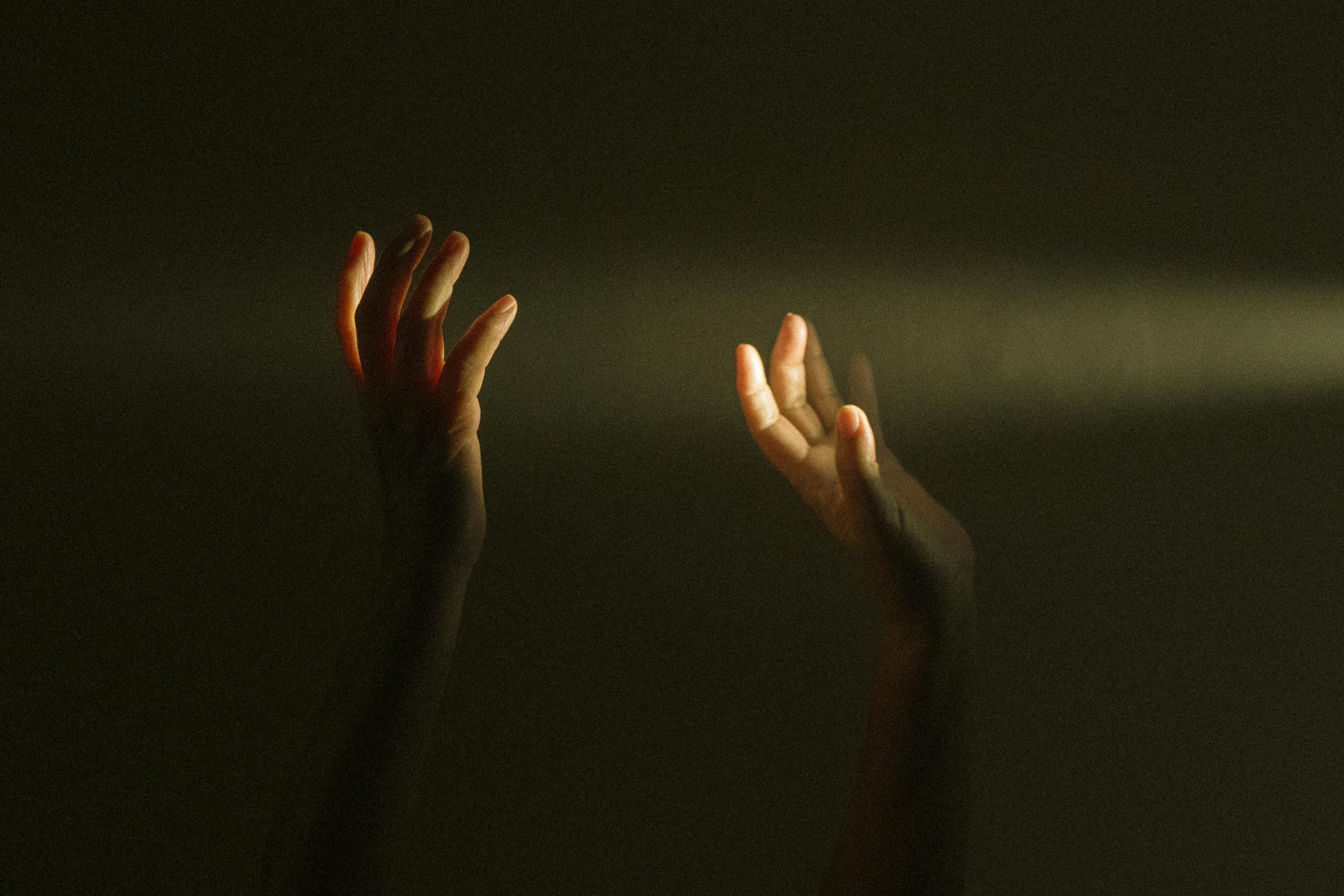 Expressive hands reaching towards ray of light symbolizing hope and mental resilience