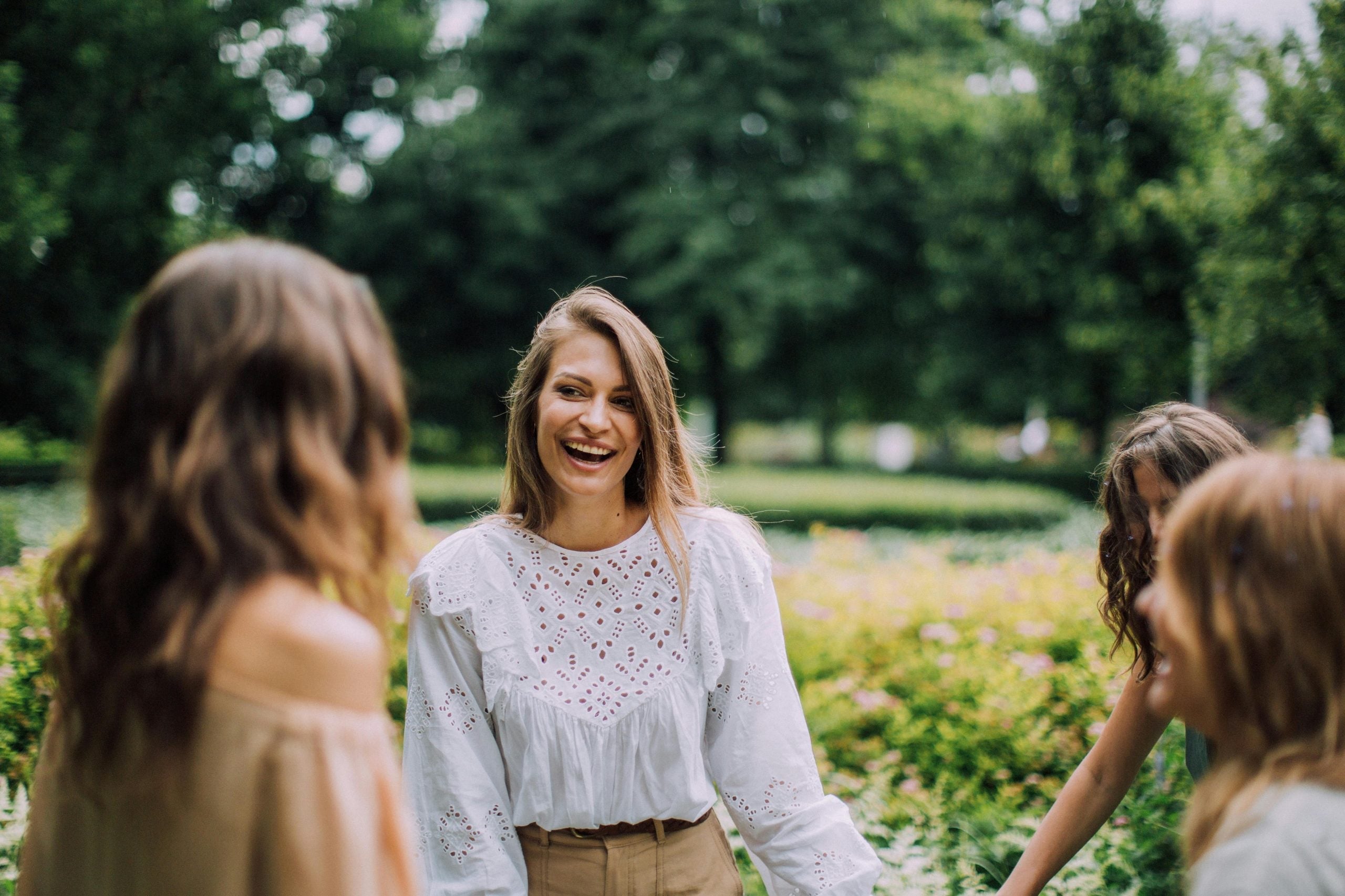 Young woman laughing with friends in sunlit park setting outdoors