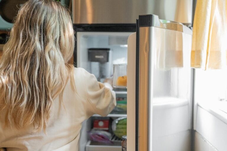 Introvert looking exhausted in kitchen after work day staring at open refrigerator with ingredients