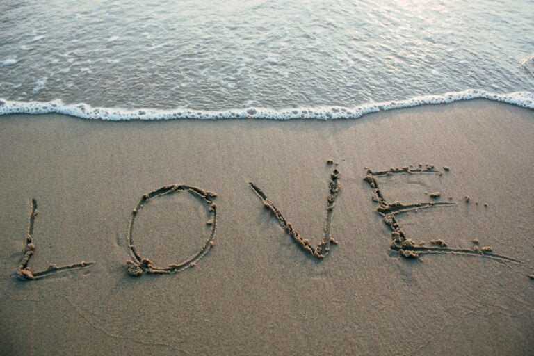 Love written in sand with ocean waves at beach evoking romance and tranquility