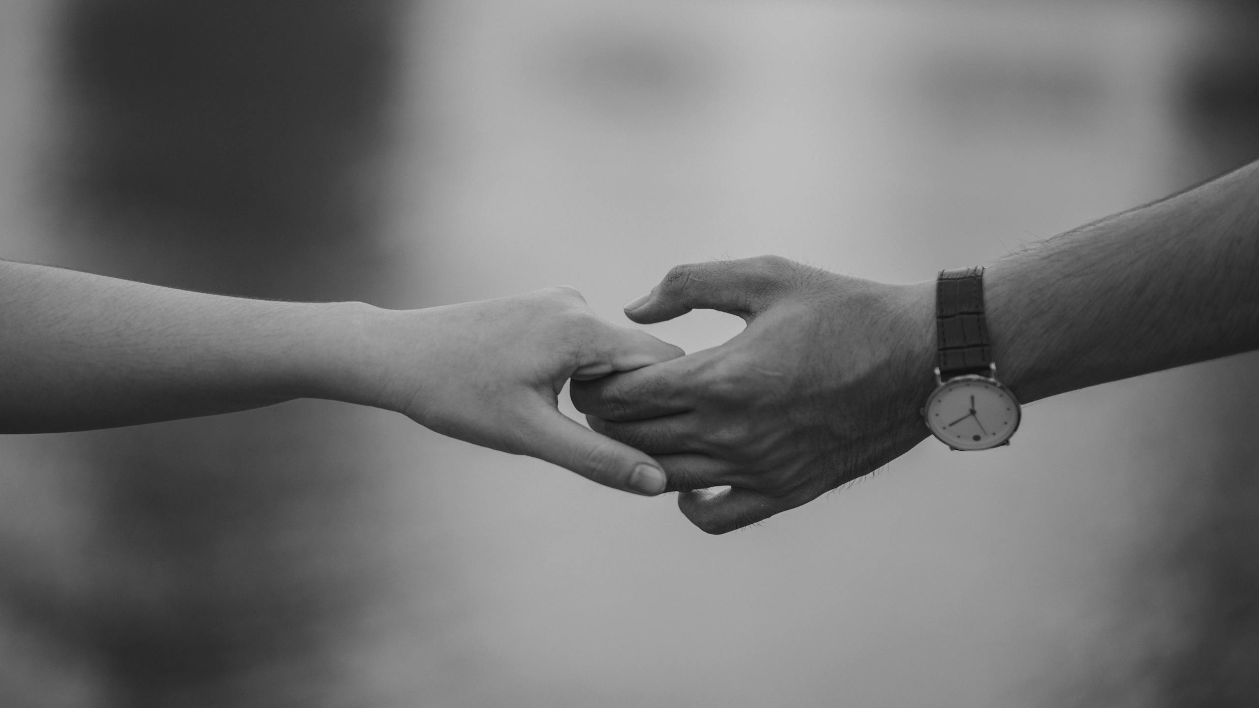 Monochrome image of two hands holding together symbolizing love and connection.
