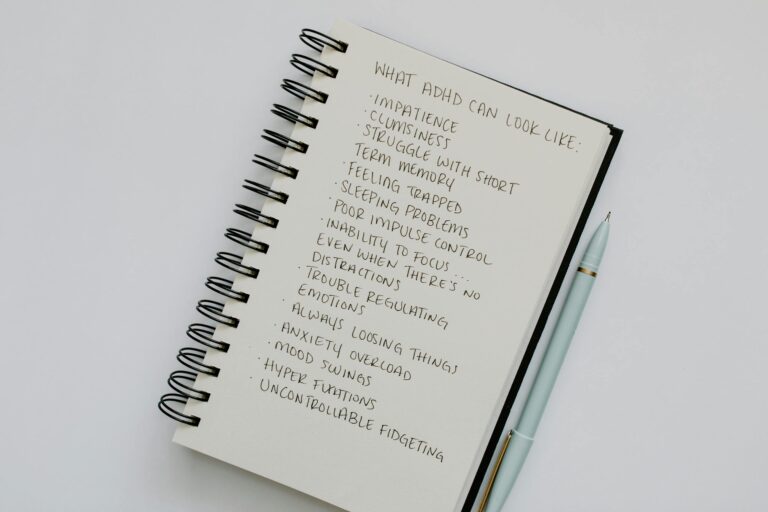 Notebook with handwritten ADHD symptoms list beside pen.