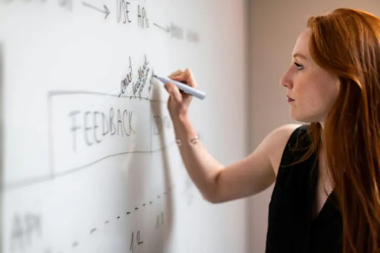 Woman writing on whiteboard, focused on analytical task and problem-solving