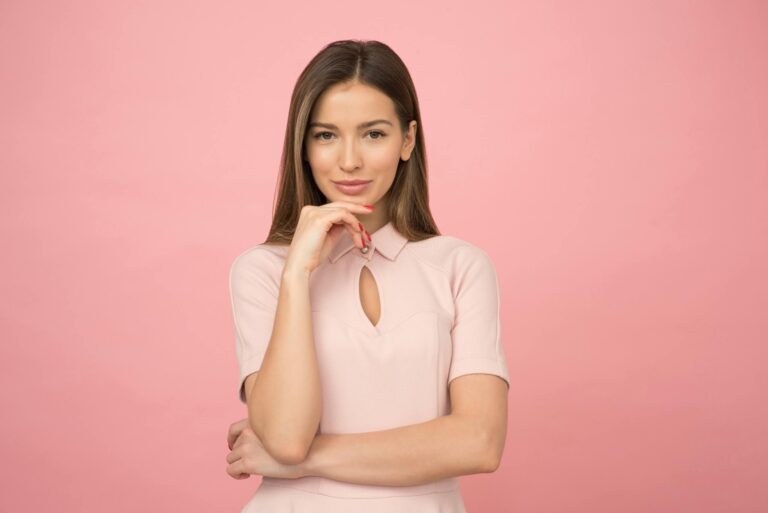Young woman posing elegantly in studio with pink background