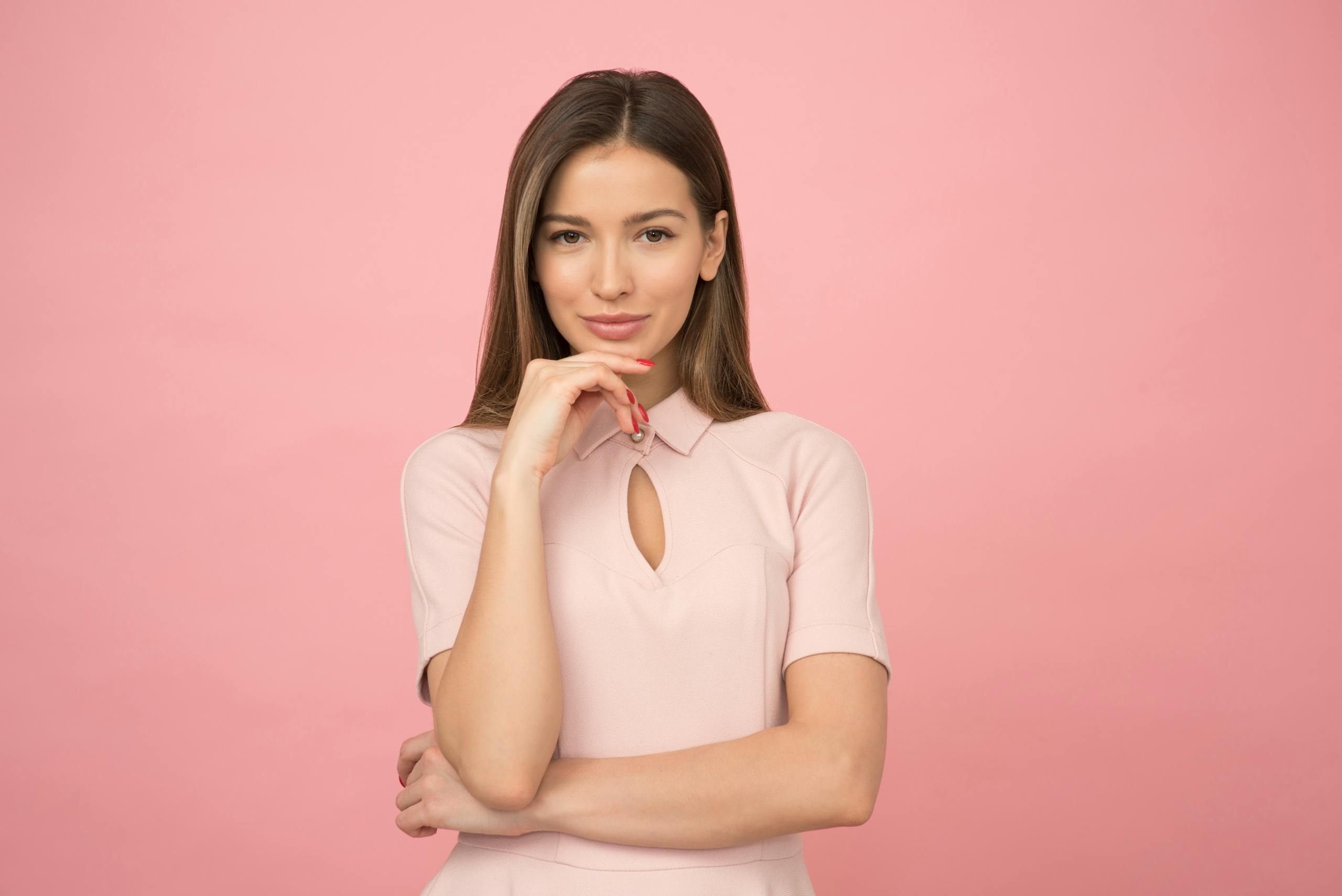 Young woman posing elegantly in studio with pink background