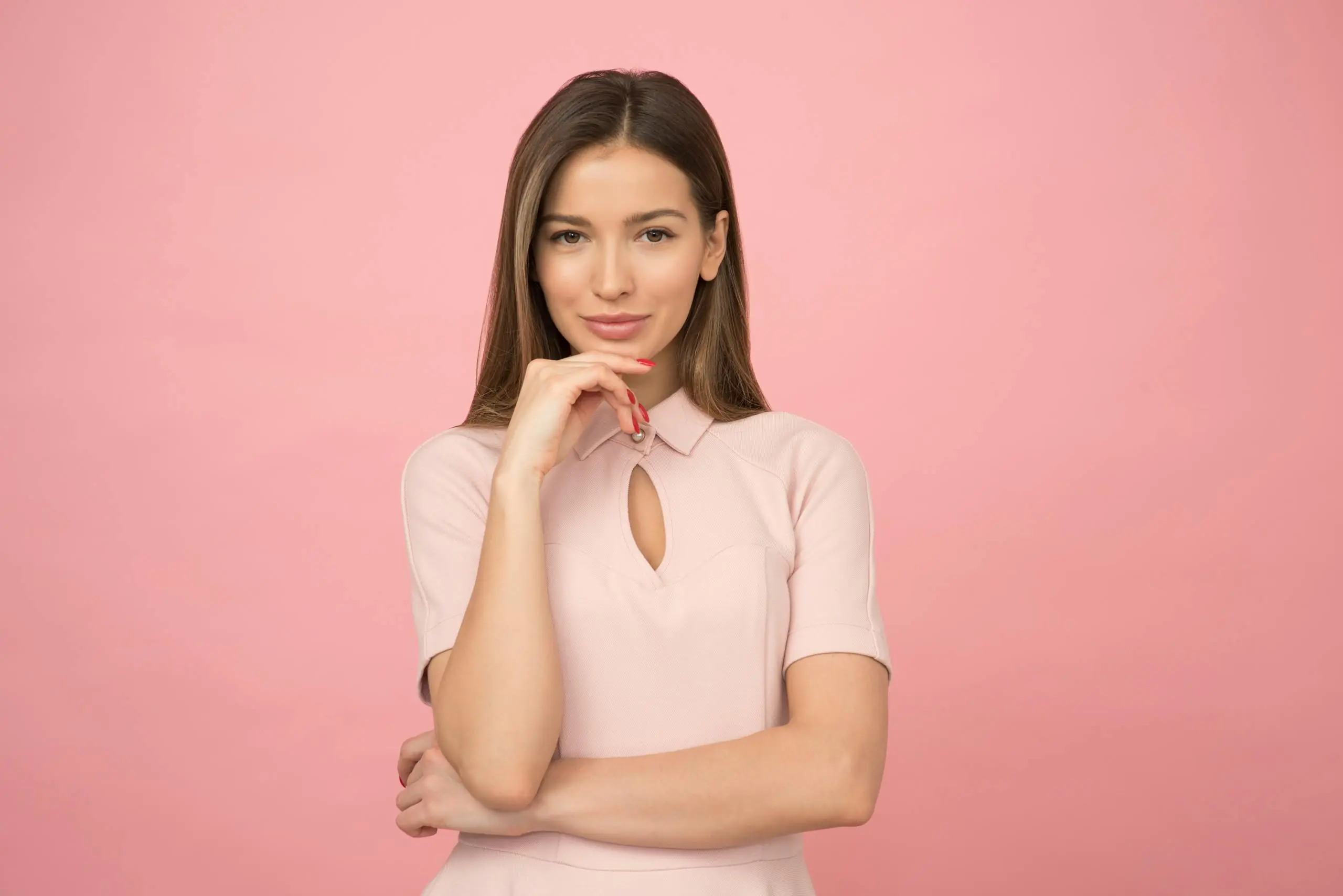 Young woman posing elegantly in studio with pink background