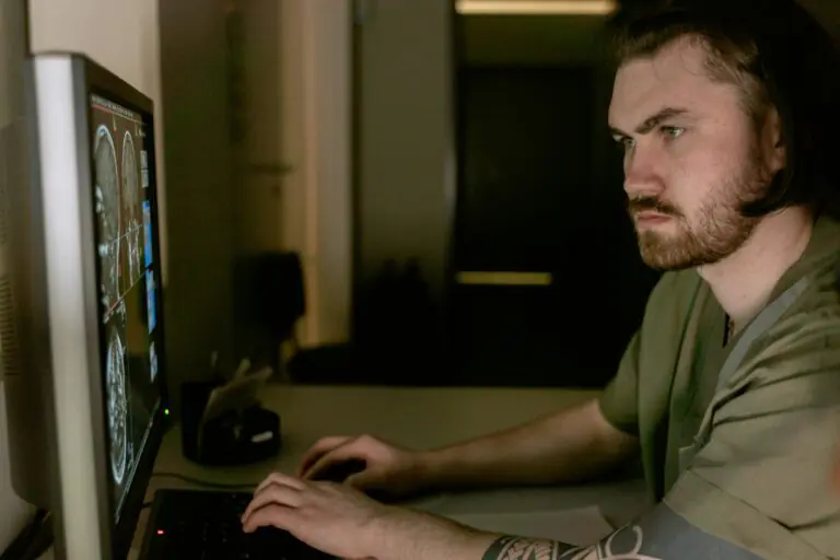 Radiologist intently studying CT scan results on computer monitor in healthcare setting.