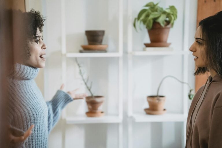 African American women in heated conflict facing each other with green plants nearby