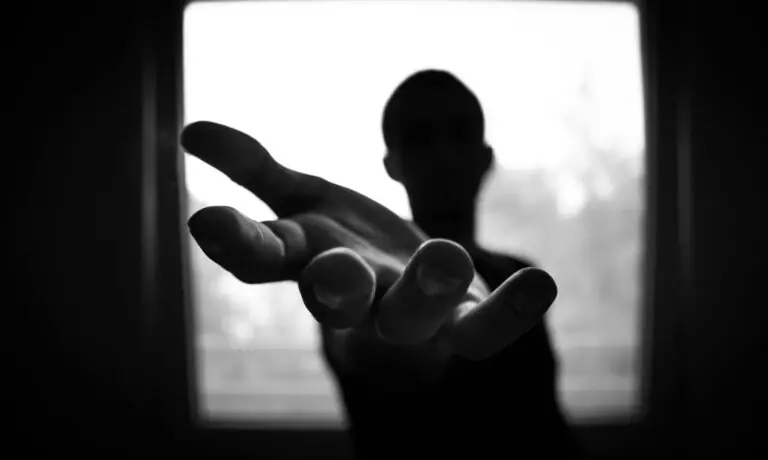 Silhouette of hand reaching out in high contrast black and white image