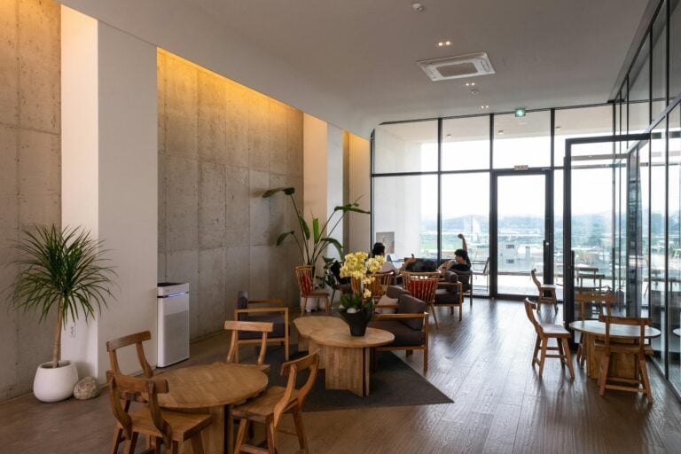 Spacious waiting room with wooden furniture and large windows offering abundant natural light.