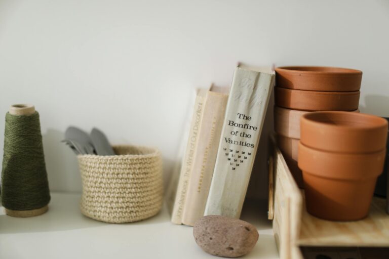 Still life of crafting tools, books, shelf with terracotta pots and colorful thread.