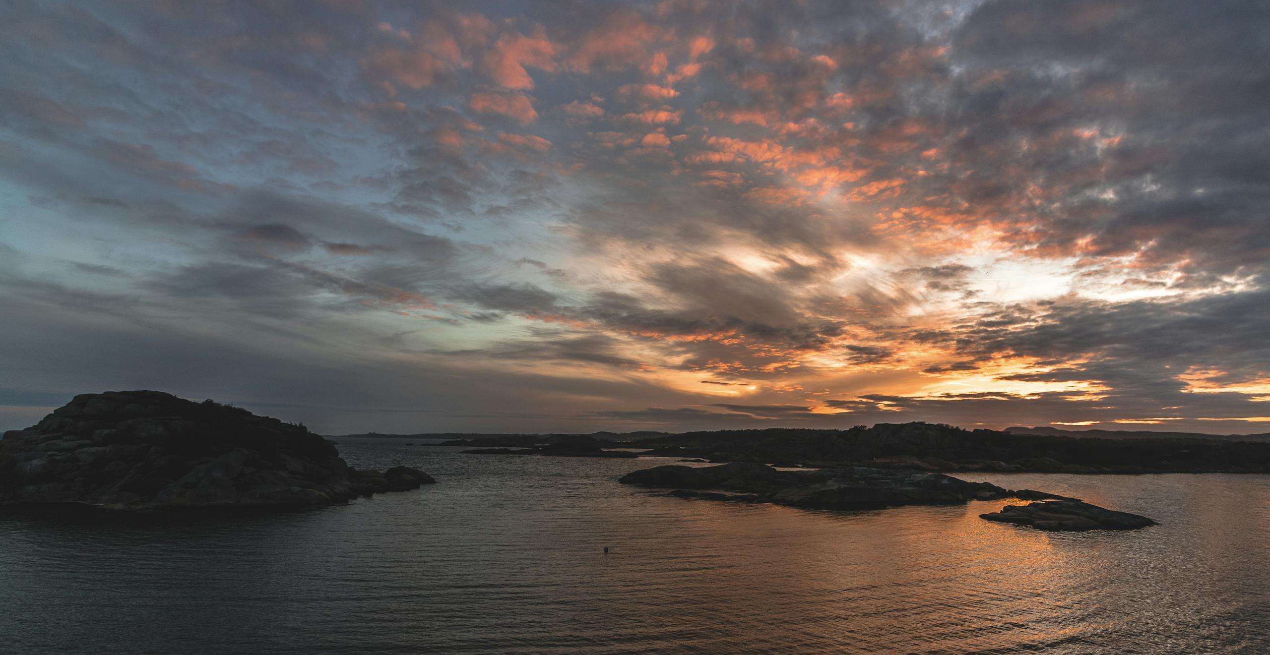 Scenic sunset with colorful sky and clouds over calm ocean and rocky shoreline