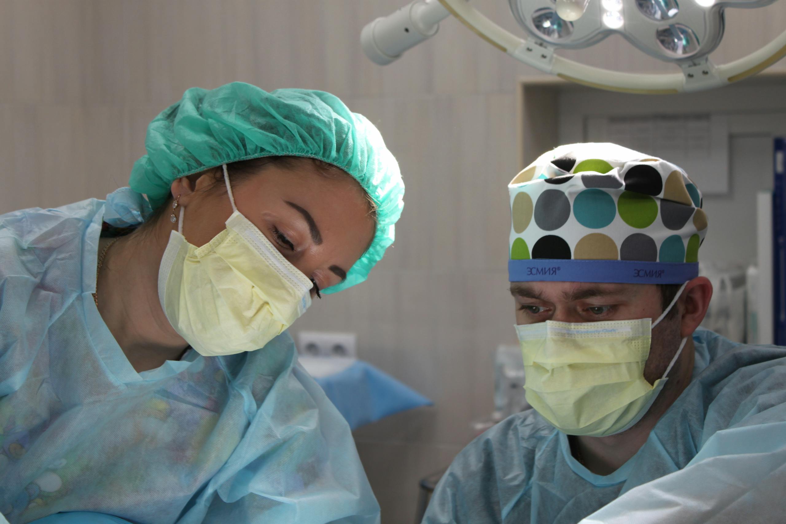 Surgeons wearing masks and scrubs performing surgical operation in hospital operating room