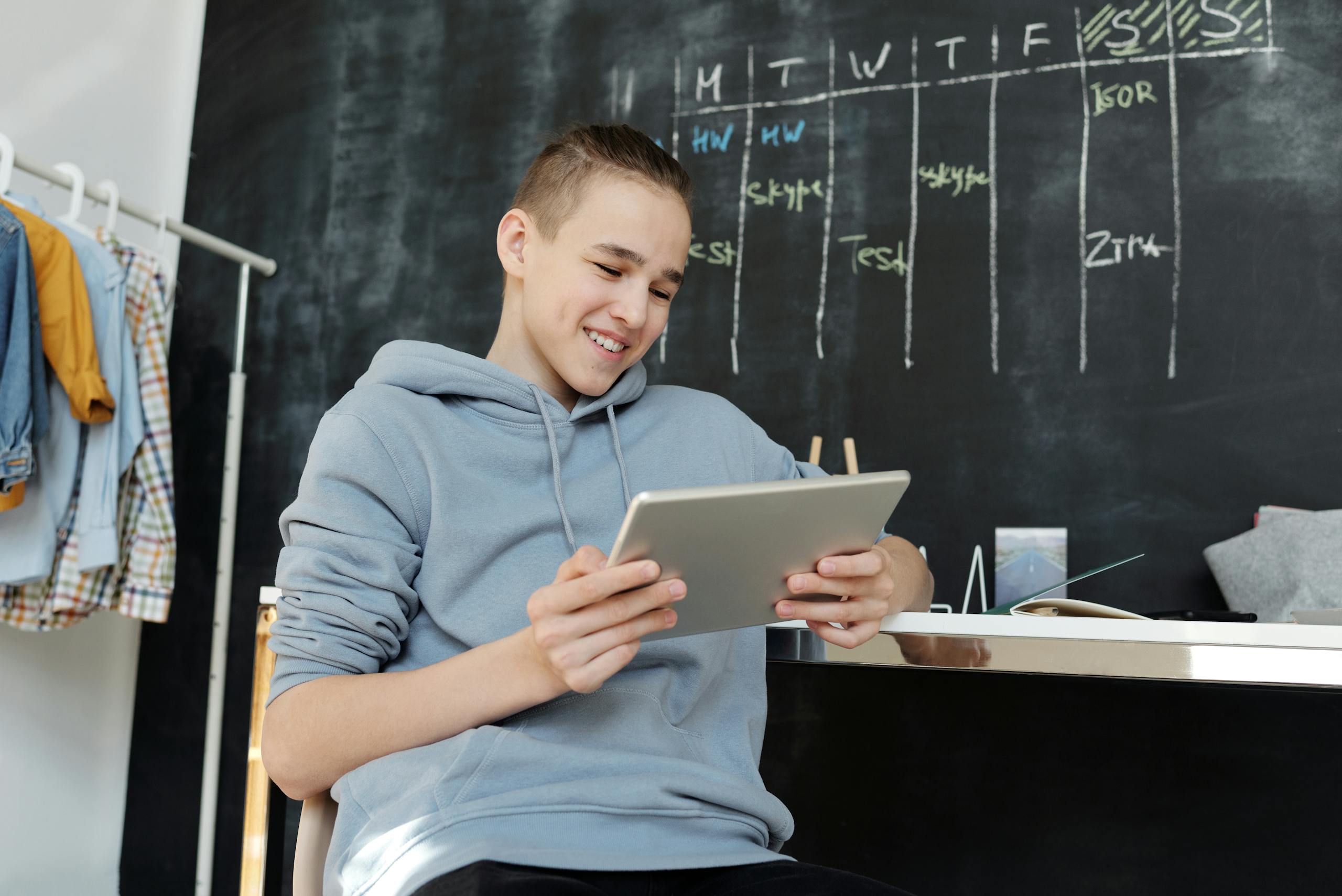 Teen smiling while using tablet indoors in relaxed classroom environment