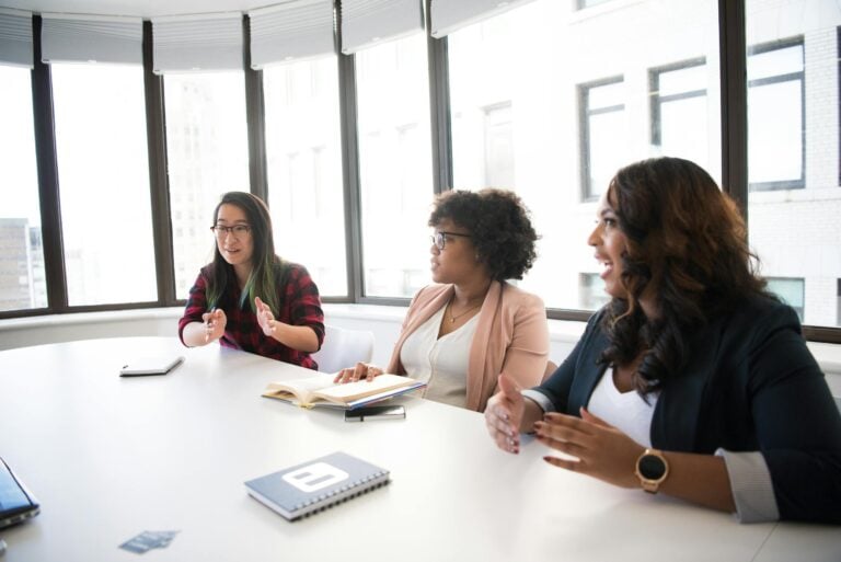 Three businesswomen engaging in productive meeting inside modern office space.