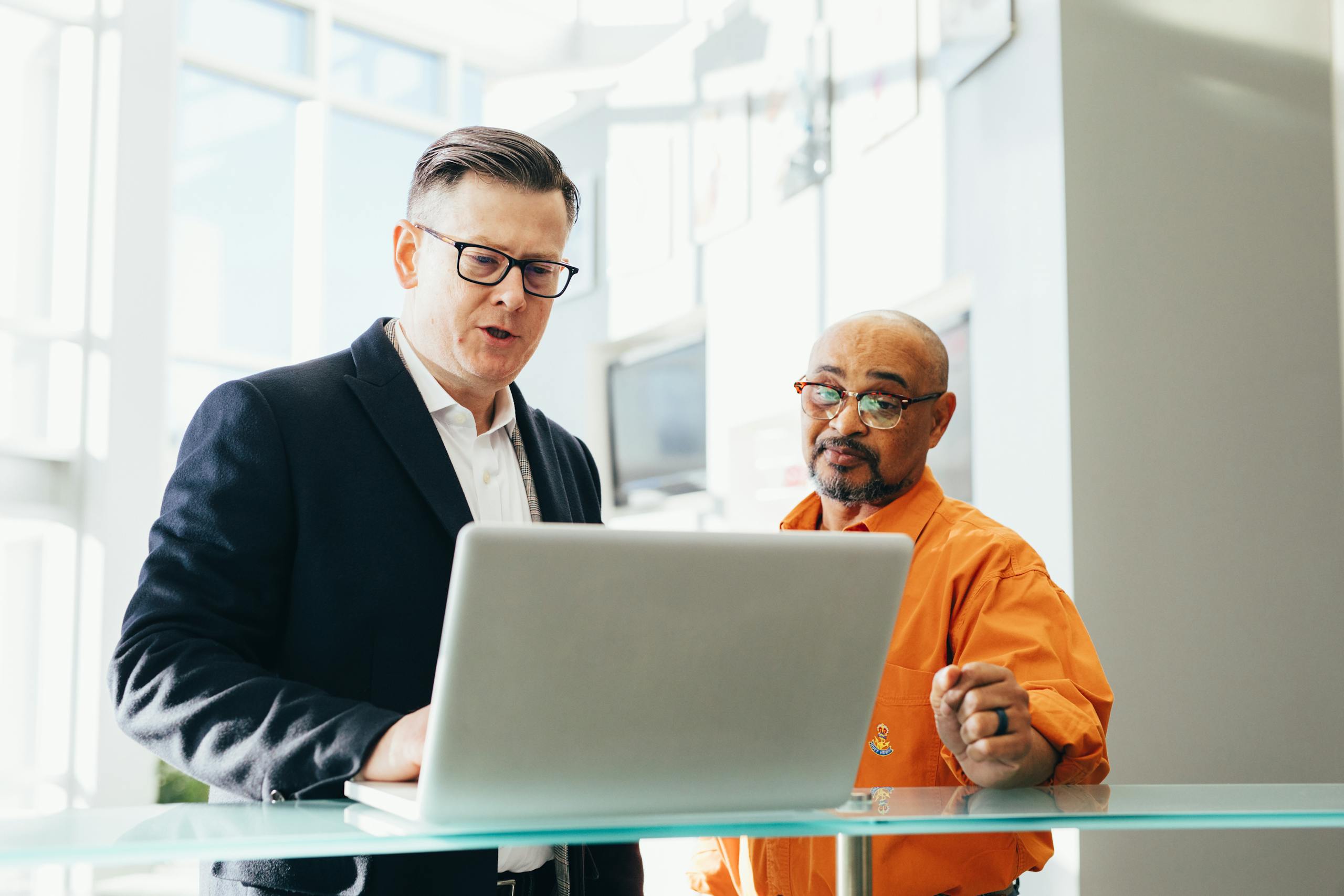 Two business professionals collaborating over laptop in modern office