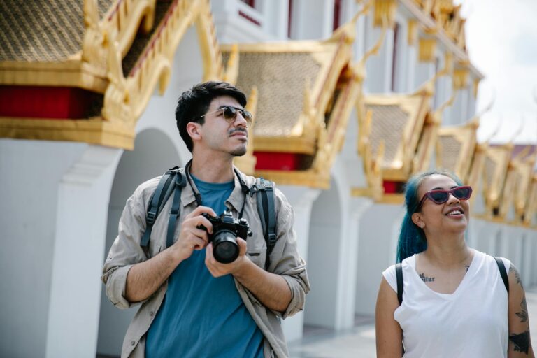 Two tourists with cameras enjoying sunny day at ornate Asian temple.