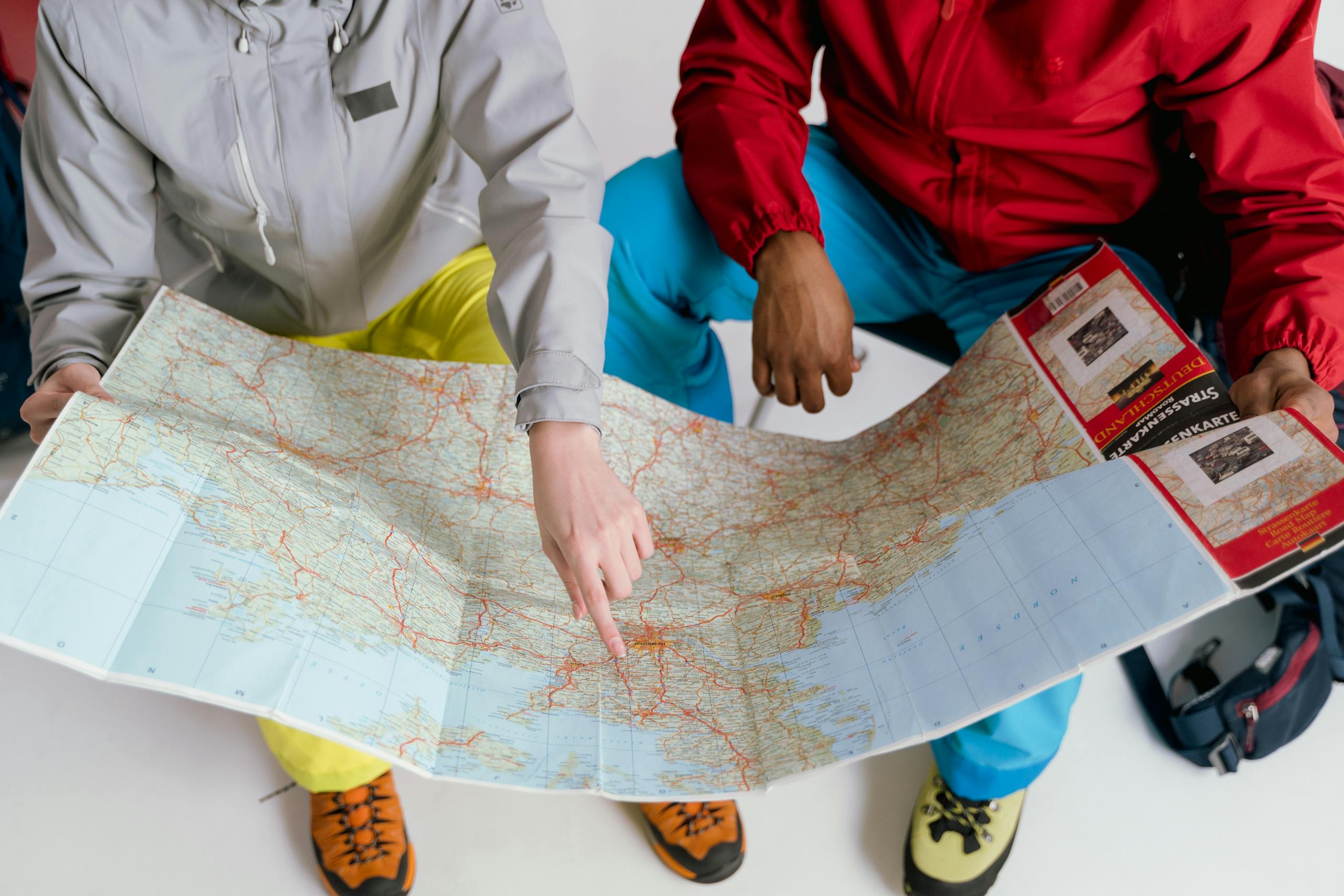 Two travelers examining detailed map for winter hiking adventure.