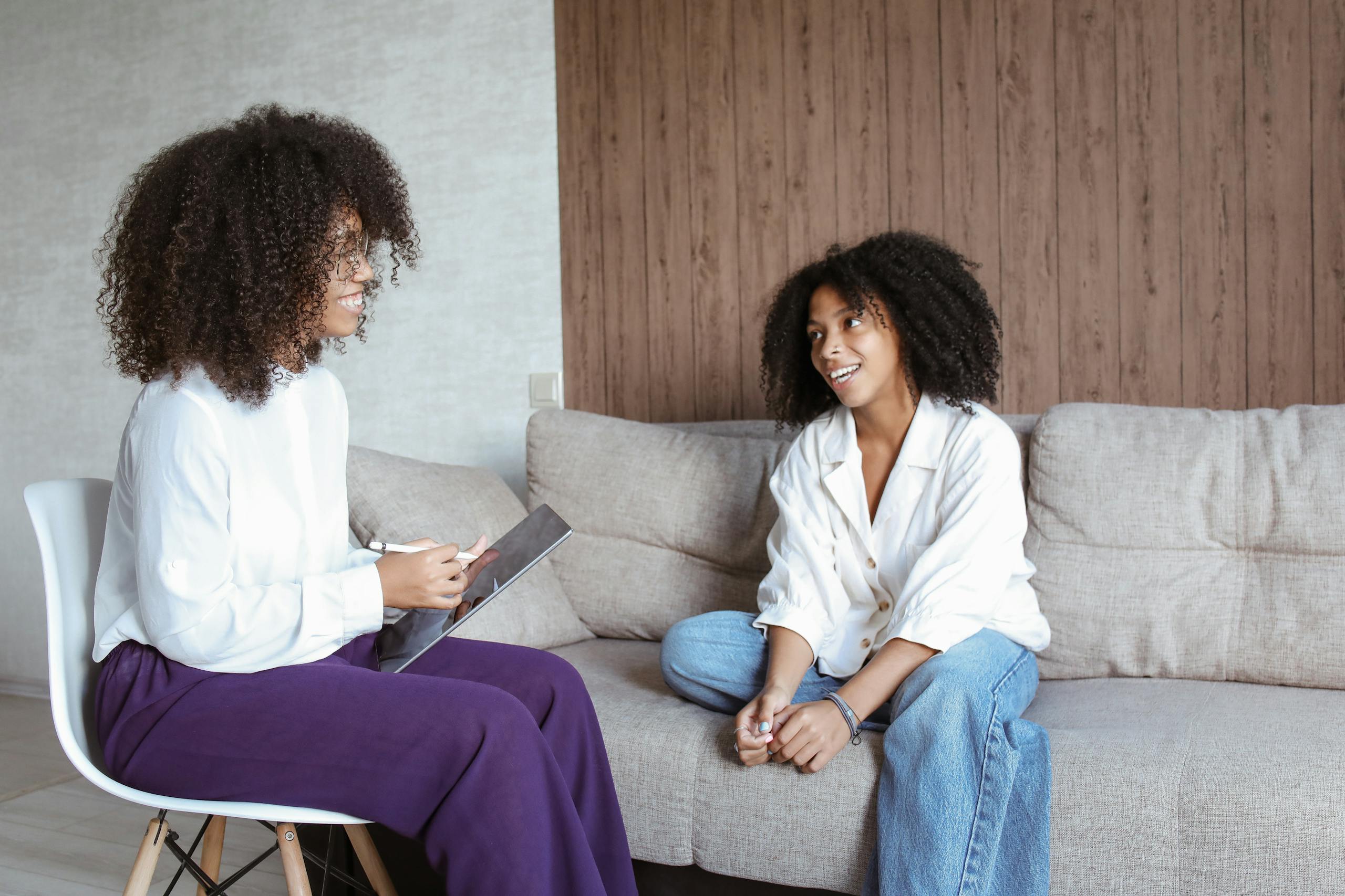 Two women in relaxed friendly conversation on sofa in cozy atmosphere.
