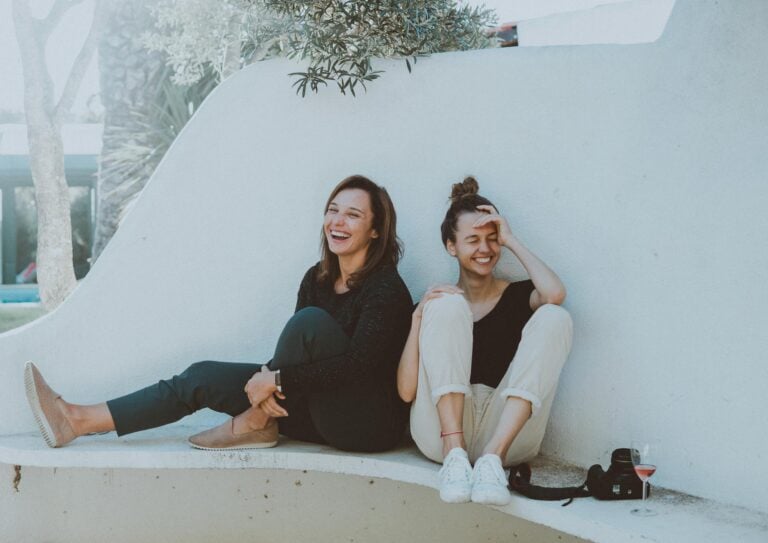 Two women laughing together outdoors enjoying friendship and leisure time