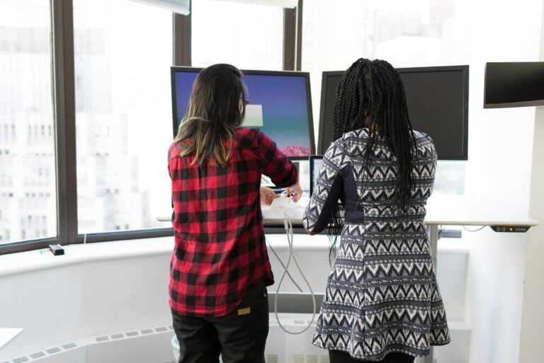 Two women working together at standing desks in bright office
