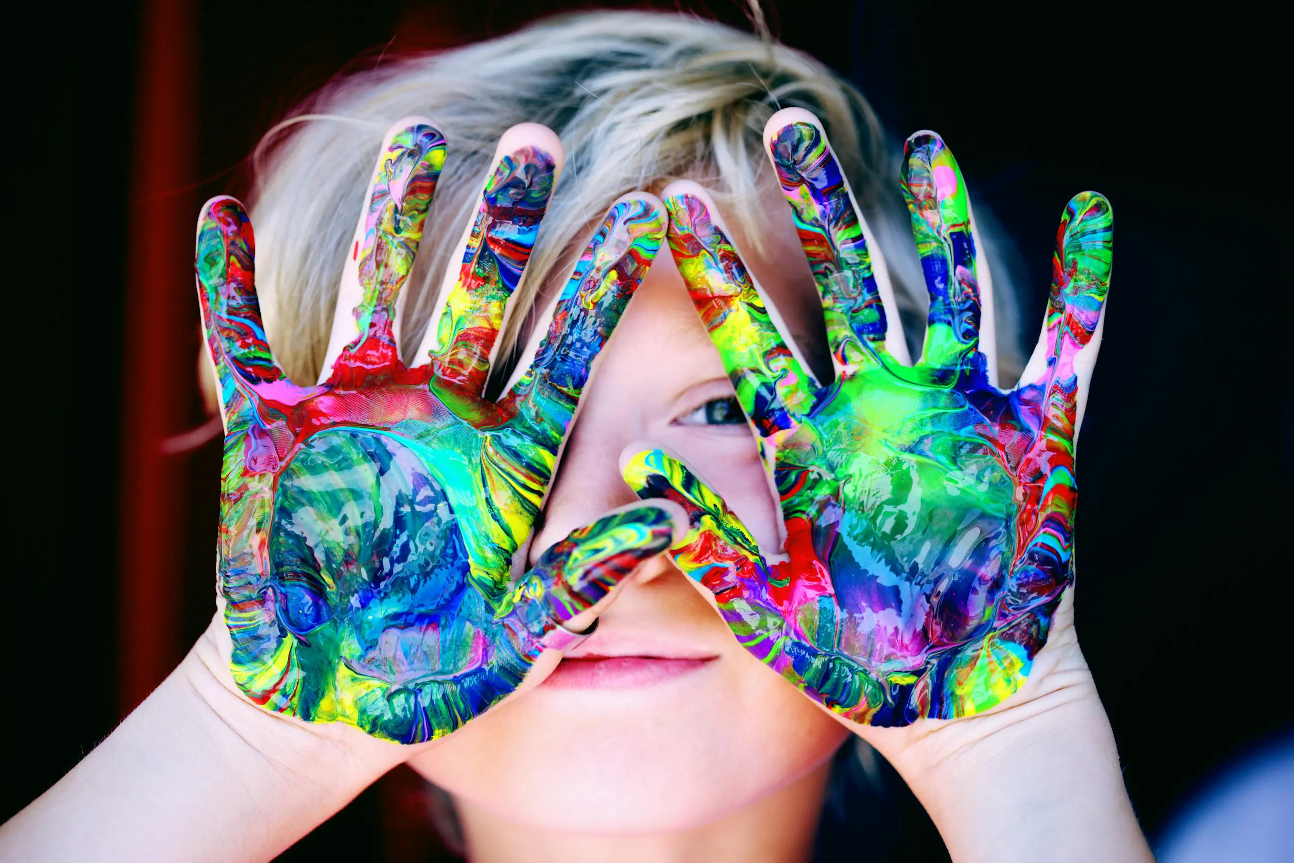 Vibrant close-up of child's hands covered in colorful paint expressing creativity and fun.