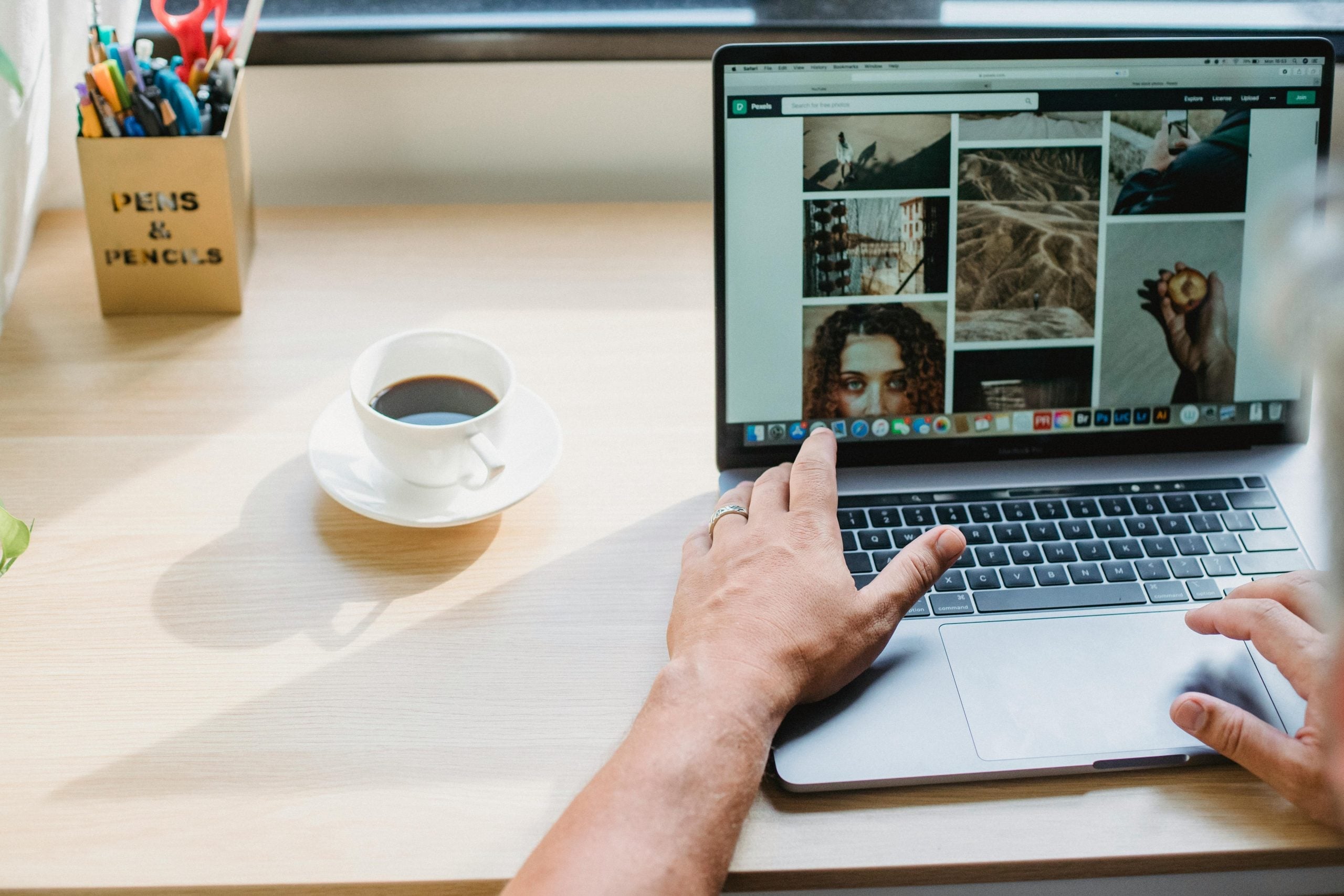 Person working on laptop with coffee, focused on creative visual content design