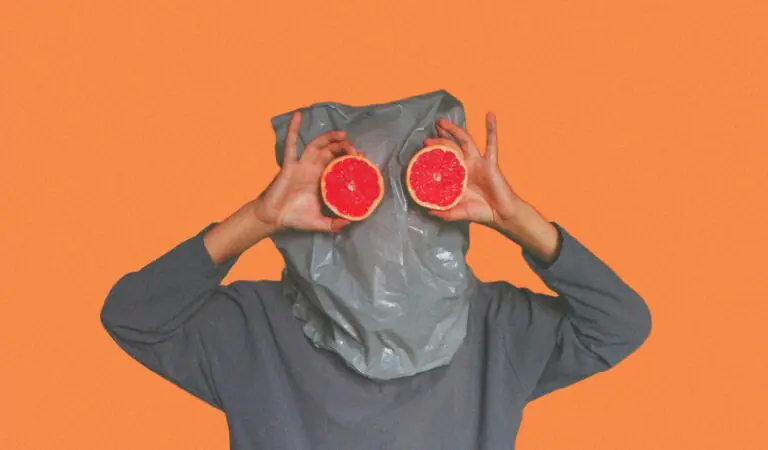 Whimsical portrait with grapefruit slices held in front of face playfully.