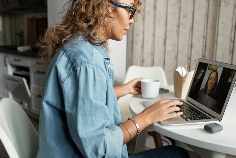 Woman enjoying video call with friend at home sipping coffee