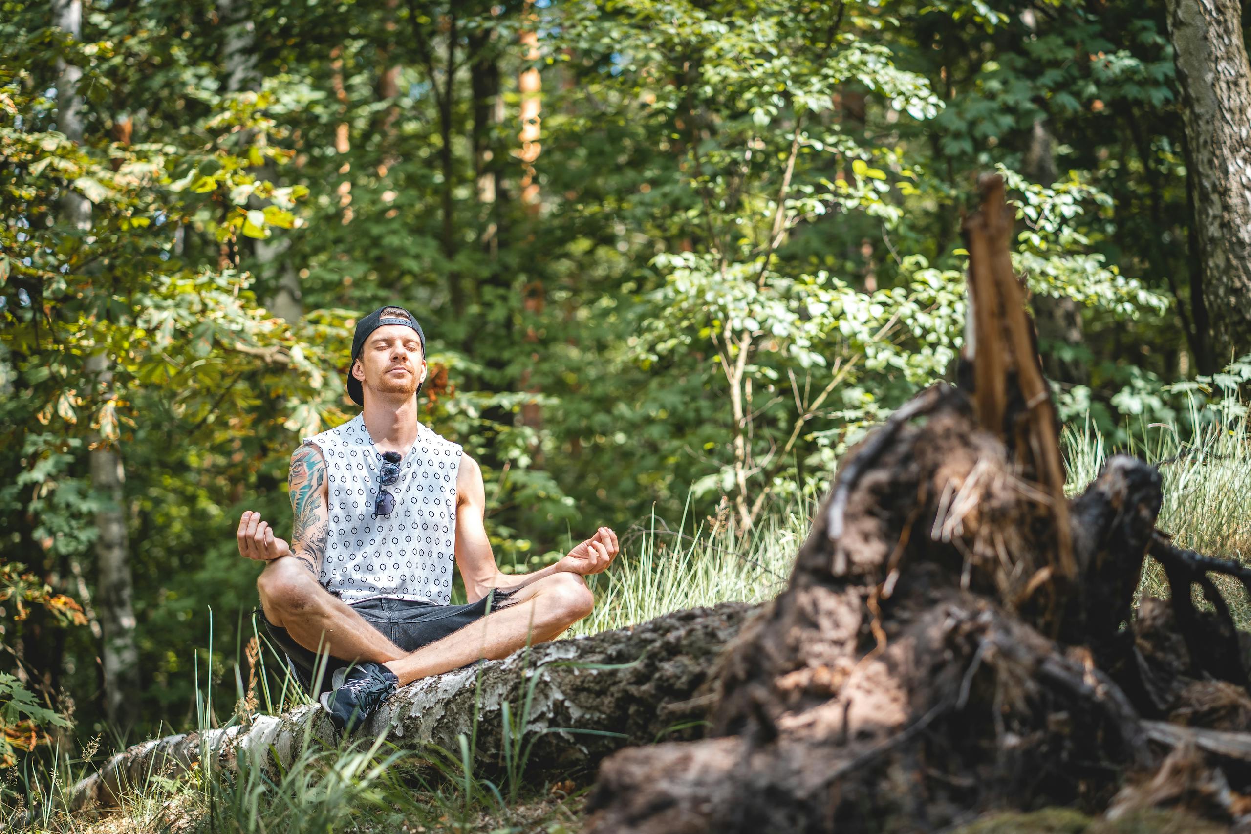 Young man meditating peacefully on wooden log in serene forest setting