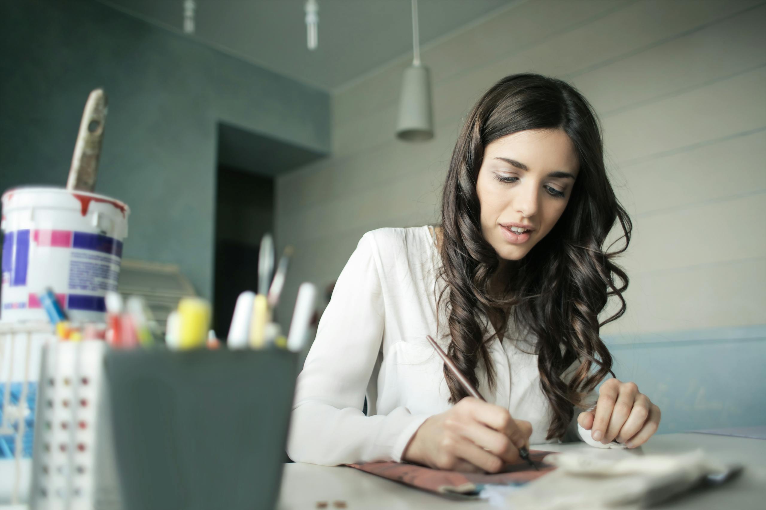 Young woman artist focused on painting at her workspace