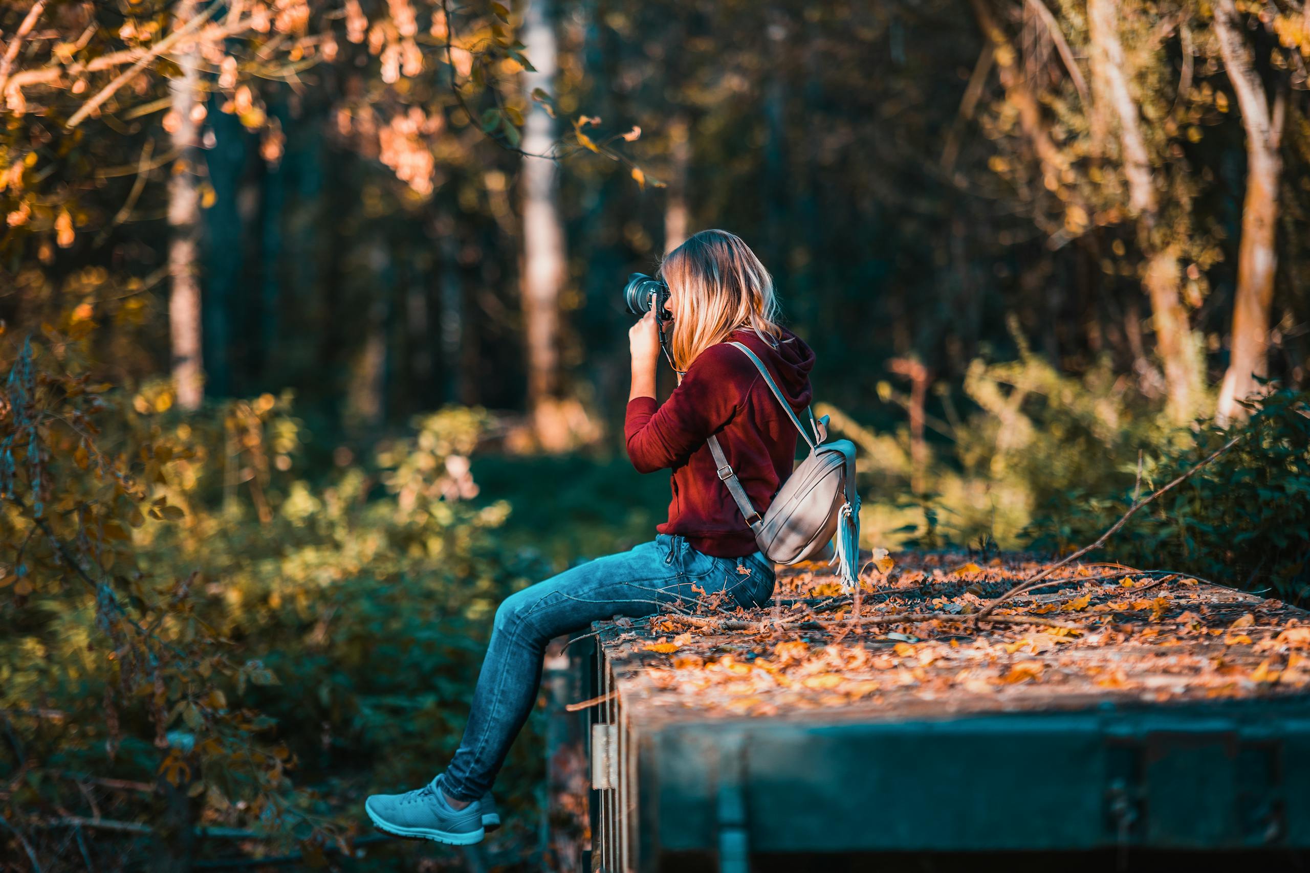 Young woman photographing in vibrant forest, embracing nature and creativity.